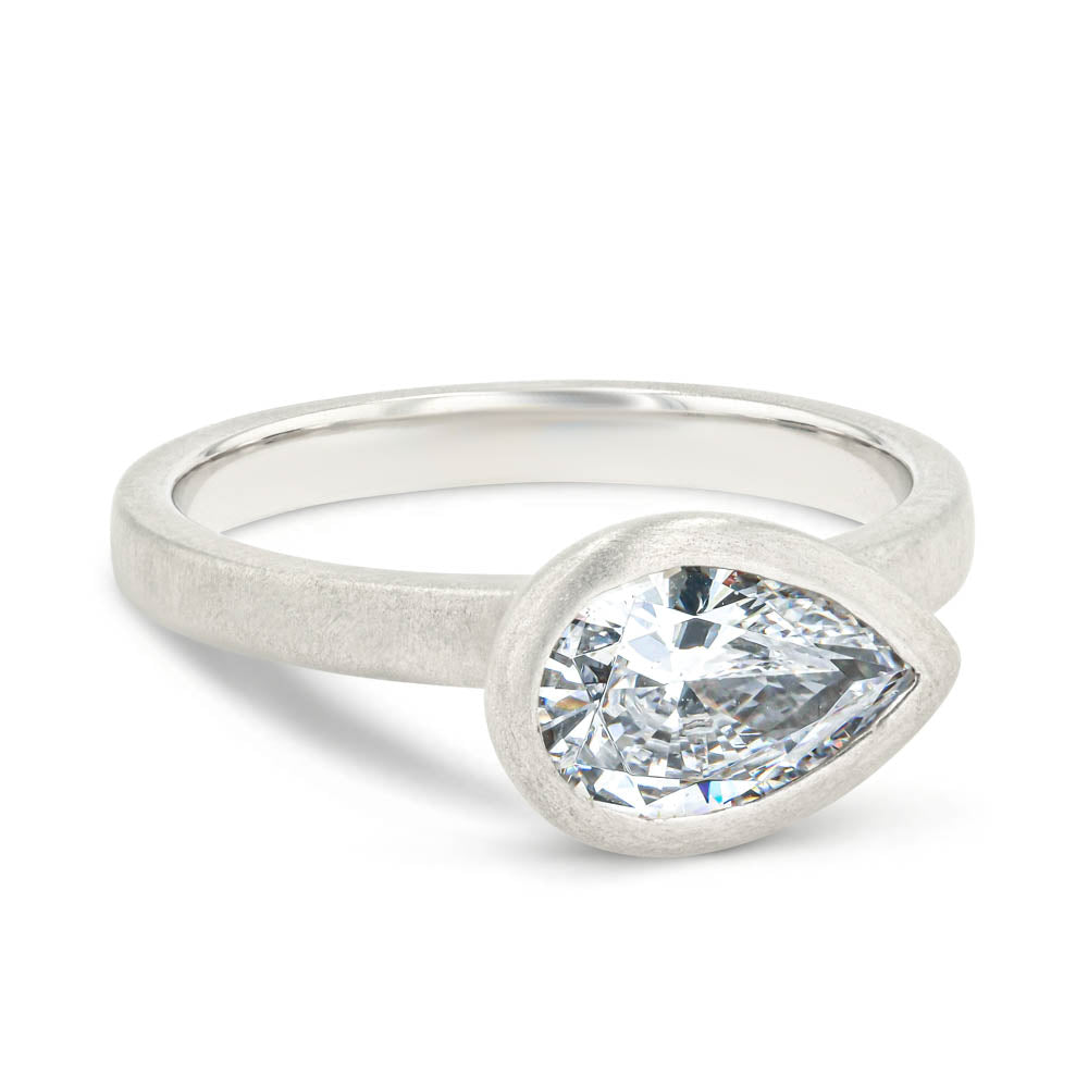 Shown in 14K White Gold with a Satin Finish|bezel set satin finish engagement ring with pear cut east to west lab grown diamonds