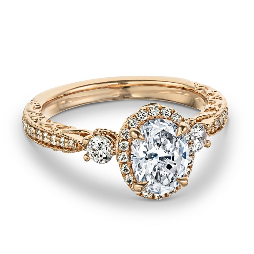 Shown with 1.5ct Oval Cut Lab Grown Diamond in 14k Rose Gold|Vintage rose gold engagement ring with diamond halo surrounding a 1.5ct oval lab grown diamond secured with claw prongs