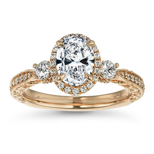 Antique style three stone engagement ring with diamond halo and accenting lab diamonds set in detailed filigree and hand carvings in 14k rose gold