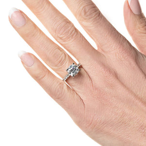 Diamond accented engagement ring with 1ct cushion cut lab grown diamond set in a four prong trellis in platinum worn on hand