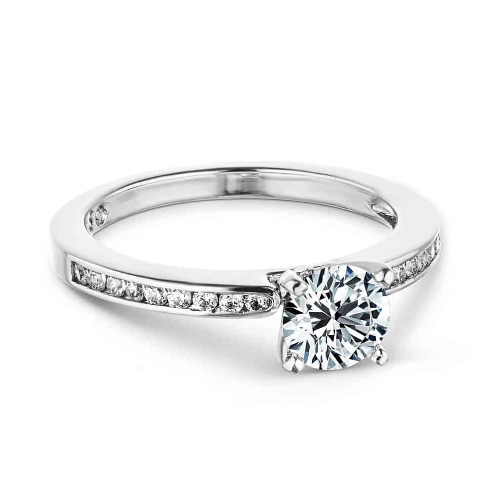 Shown with a 1.0ct Round cut Lab-Grown Diamond with channel set accenting diamonds in recycled 14K white gold with matching wedding band 