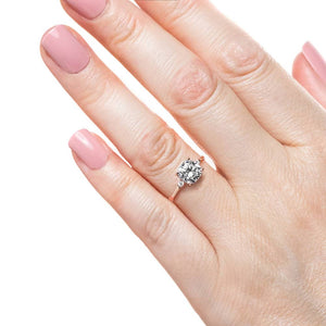 Engagement ring with 1ct cushion cut lab grown diamond with two diamond side stones in 14k rose gold worn on hand