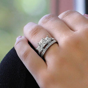 Three stone engagement ring with princess cut lab grown diamonds set in 14k white gold shown worn on hand with accented band