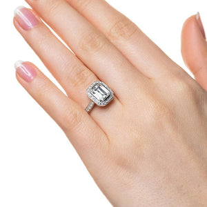 Vintage style diamond accented halo engagement ring with 1ct emerald cut lab grown diamond in 14k white gold worn on hand