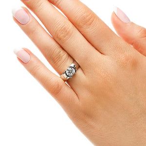 Modern solitaire engagement ring with half bezel set 1ct round cut lab grown diamond in 14k white gold worn on hand