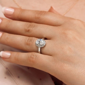 Cute pave set diamond accented halo engagement ring with 1ct oval cut lab grown diamond in platinum worn on hand