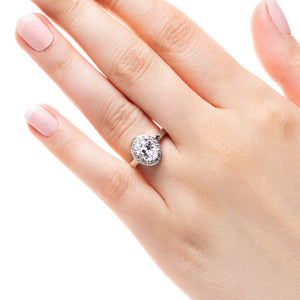 Diamond accented halo engagement ring with 1ct oval cut lab grown diamond in platinum band worn on hand