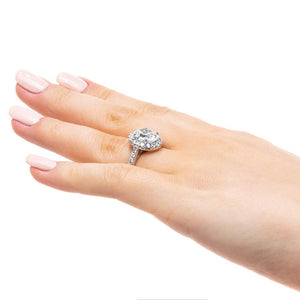 Diamond accented halo engagement ring with 2ct oval cut lab grown diamond in 14k white gold band worn on hand sideview