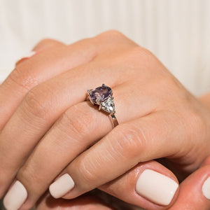 Unique three stone gemstone engagement ring with 1ct oval cut lab grown alexandrite and two 0.50 triangle cut diamond side stones in 14k white gold band shown worn on hand