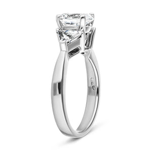 Three stone engagement ring with 1ct oval cut lab grown diamond and two 0.50 triangle cut diamond side stones in 14k white gold band shown from side