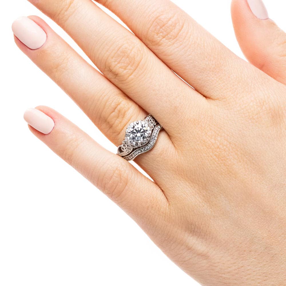 Shown with a 1.0ct Round cut Lab-Grown Diamond with diamond accented halo and filigree detailed band in recycled 14K white gold with matching wedding band, can be purchased together for a discounted price