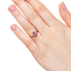 Hidden halo engagement ring with 2ct round cut lab created pink sapphire in 14k rose gold band worn on hand