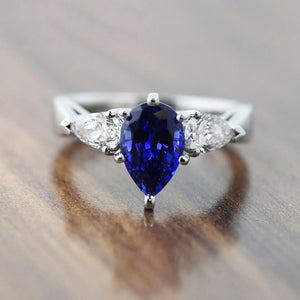 Three stone blue and white engagement ring with 1ct pear cut lab created blue sapphire with lab grown diamond side stones set in platinum