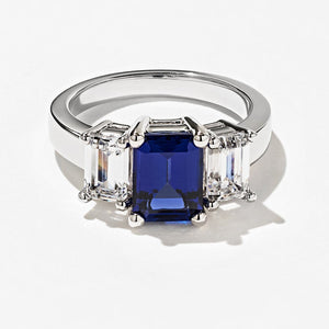 Gorgeous unique three stone engagement ring with 1ct emerald cut lab grown blue sapphire center stone and two lab grown diamond side stones in 14k white gold setting