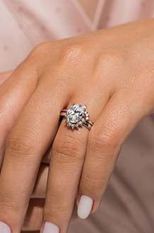 A lady's hand featuring a MiaDonna best seller, a yellow gold Matilda Halo Engagement Ring with a round cut center stone showcased within a unique floral halo of accenting Lab Grown Diamonds. 