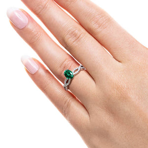 Antique style diamond accented engagement ring with 1ct oval cut lab created emerald in 14k white gold worn on hand