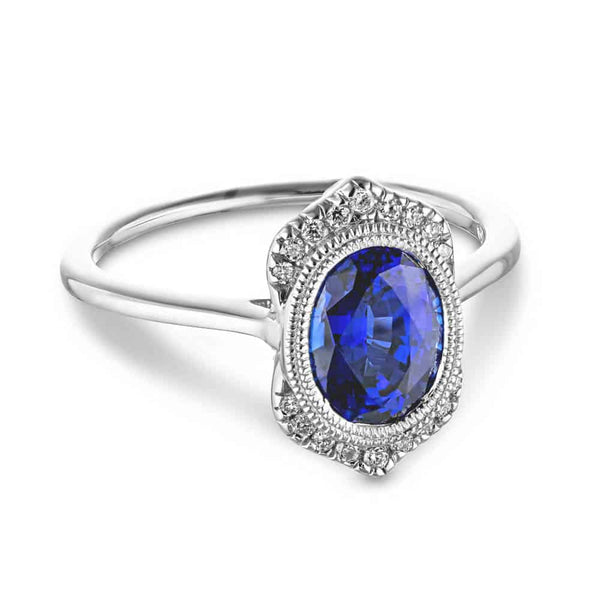 Shown with 2ct Oval Cut Lab Grown Blue Sapphire in 14k White Gold|Antique style blue sapphire engagement ring with milgrain bezel and accenting diamonds set in 14k white gold