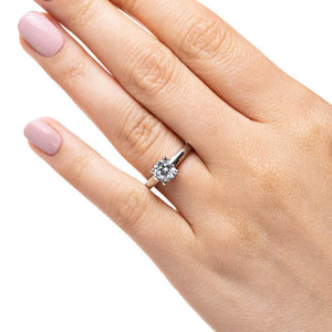 Simple traditional solitaire engagement ring with 1ct round cut lab grown diamond set in 14k white gold shown worn on hand