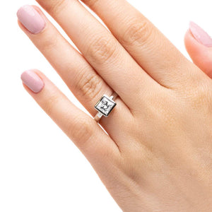 Modern sleek minimalistic solitaire engagement ring with 1.5ct princess cut bezel set lab grown diamond in 14k white gold worn on hand