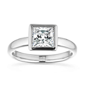 Modern sleek minimalistic solitaire engagement ring with 1.5ct princess cut bezel set lab grown diamond in 14k white gold shown from front