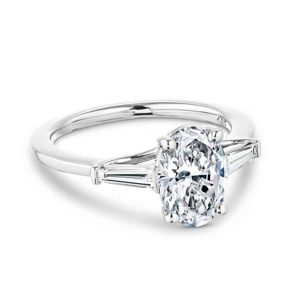 Shown with 2ct Oval Cut Lab Grown Diamond set in 14k White Gold|Beautiful three stone engagement ring with trellis set 2ct oval cut lab grown diamond amid baguette side stones in 14k white gold