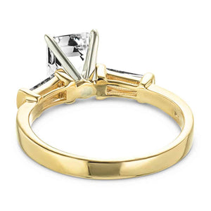 Modern three stone engagement ring with two baguette cut recycled diamond side stones and a 1.5ct emerald cut lab grown diamond center in 14k yellow gold shown from back