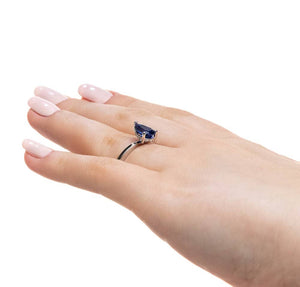 Hidden halo engagement ring with 1ct pear cut lab grown blue sapphire in 14k white gold band shown on hand