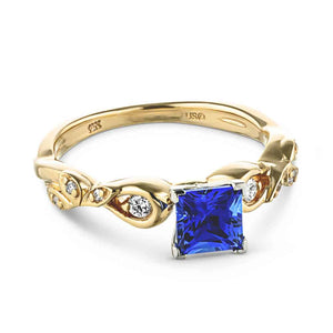 Nature inspired design engagement ring with diamond accented band and a 1ct princess cut lab created blue sapphire in 14k yellow gold