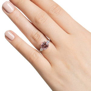 Three stone engagement ring with 2ct lab created champagne pink sapphire center stone and pear diamond side stones in 14k white gold shown worn on hand