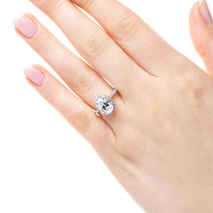 Diamond accented halo engagement ring with 1ct pear cut lab grown diamond in 14k white gold worn on hand