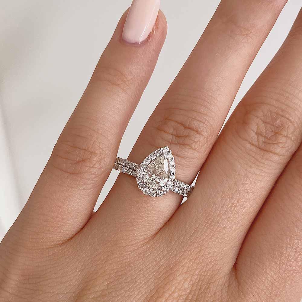 Shown with a 1.0ct Pear cut Lab-Grown Diamond with a diamond accented halo and band in recycled 14K white gold with matching wedding band| halo diamond accented engagement ring Shown with a 1.0ct Pear cut Lab-Grown Diamond with a diamond accented halo and band in recycled 14K white gold with matching wedding band