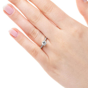 Diamond accented solitaire engagement ring with 4 prong set round cut lab grown diamond in 14k white gold worn on hand