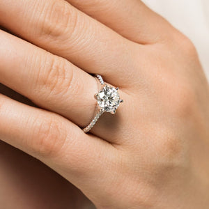 Gorgeous conflict free diamond accented engagement ring with 1.5ct round cut lab grown diamond set in 6 prong 14k white gold setting worn on hand