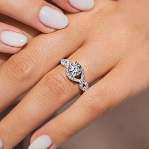Gorgeous conflict free diamond accented engagement ring with twisted wavy band design and a 1ct round cut lab grown diamond set in 14k white gold worn on hand