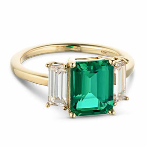 Gorgeous three stone engagement ring with 2ct emerald cut lab created emerald center between baguette cut lab diamonds set in 14k yellow gold