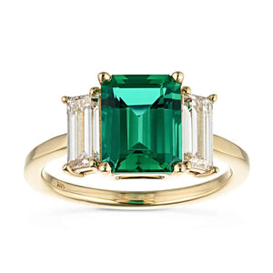 Stunning ethical three stone engagement ring with 2ct emerald cut lab created emerald center between baguette cut lab diamonds set in 14k yellow gold