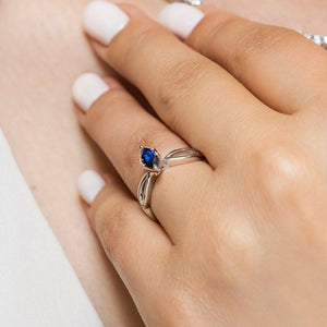 Unique nature inspired solitaire engagement ring with a 1ct marquise cut lab grown blue sapphire in twisted metal design 14k white gold band worn on hand