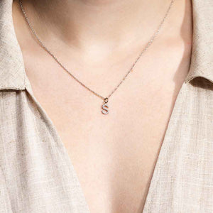 Woman wearing an S Initial pendant in 14 carat white gold embedded with  lab grown diamonds from MiaDonna