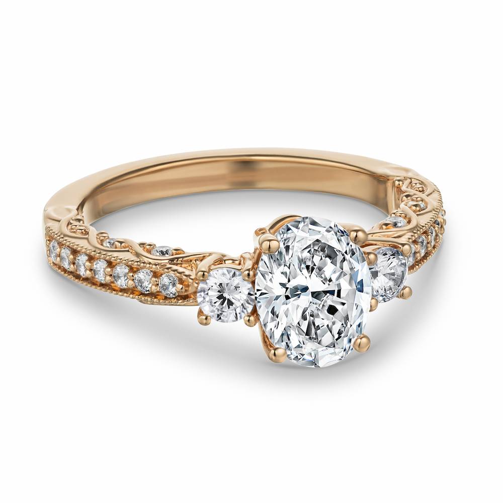 Shown with 1ct Oval cut Lab Grown Diamond in 14k Rose Gold| Vintage style rose gold engagement ring featuring beautiful milgrain detailing surrounding accenting diamonds with a 1ct oval cut lab created diamond surrounded by two round cut diamond shoulder stones