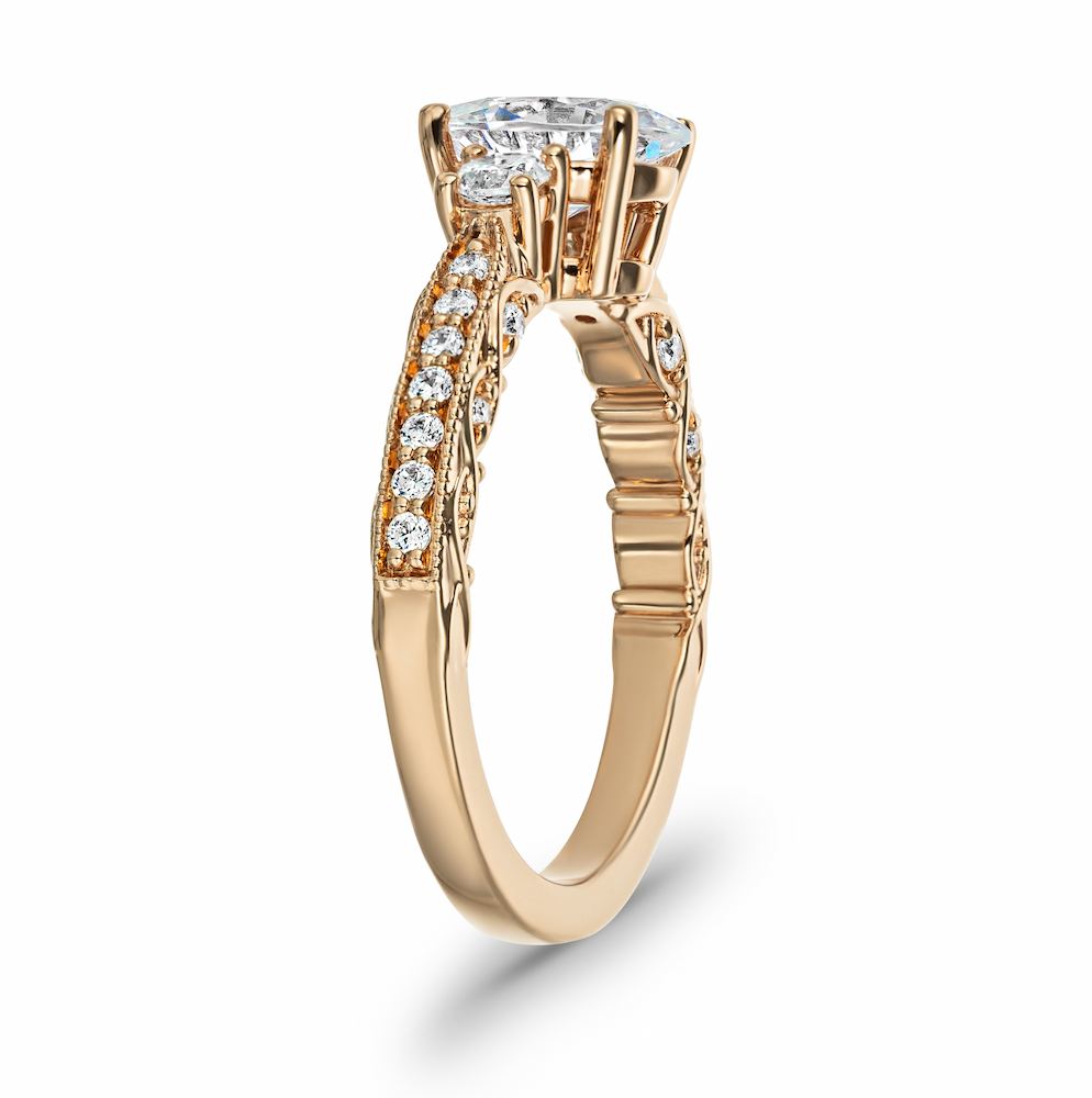 Shown with 1ct Oval cut Lab Grown Diamond in 14k Rose Gold| Vintage style rose gold engagement ring featuring beautiful milgrain detailing surrounding accenting diamonds with a 1ct oval cut lab created diamond surrounded by two round cut diamond shoulder stones