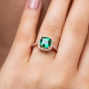 Beautiful unique diamond accented halo engagement ring with 1ct cushion cut lab created emerald in 14k yellow gold worn on hand