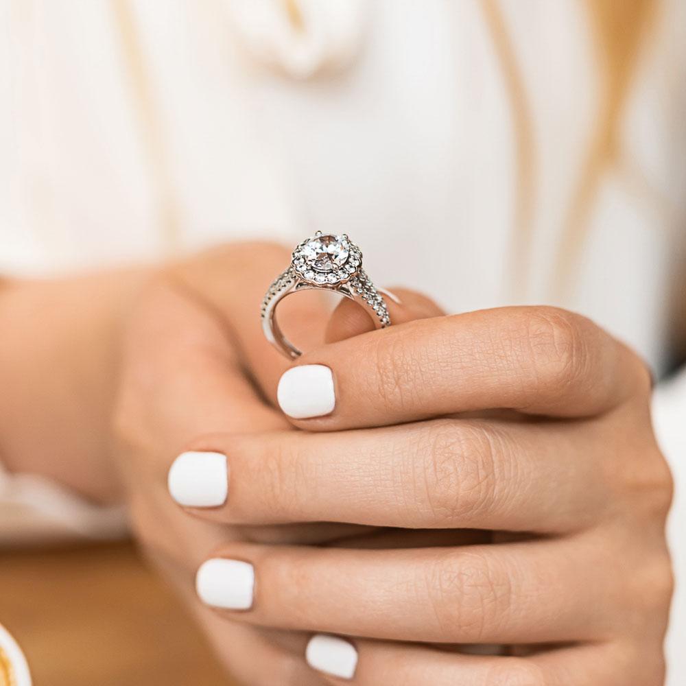 Shown with 1ct Oval Cut Lab Grown Diamond in 14k White Gold|Unique nature inspired flower halo engagement ring with diamond accented split shank holding a 1ct oval cut lab grown diamond in 14k white gold