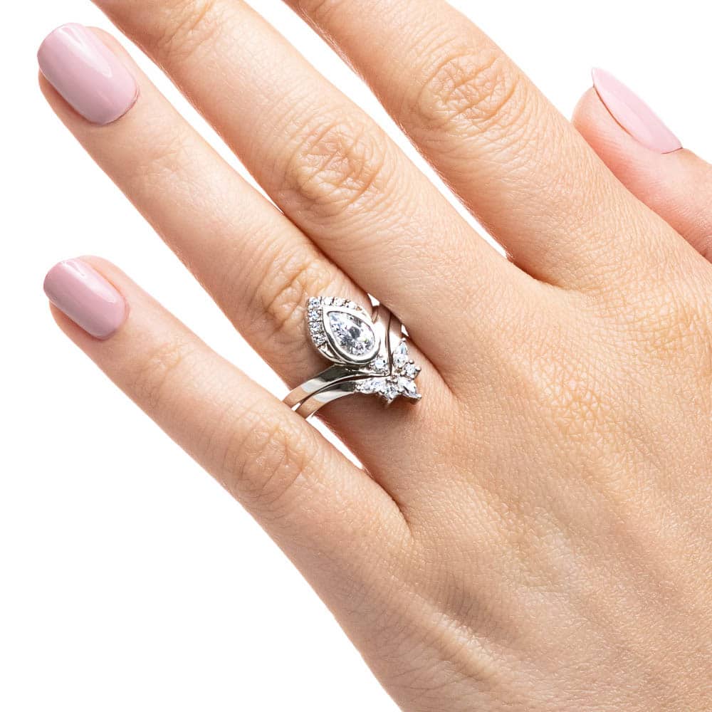 Shown with a bezel set 1.0ct Pear cut Lab-Grown Diamond with a half diamond halo in recycled 14K white gold with matching wedding band, can be purchased as a set for a discounted price 