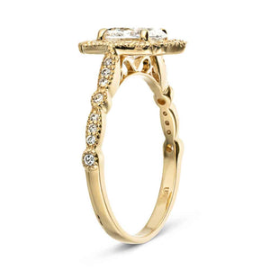 Romantic beautiful engagement ring reminiscent of Paris France architecture feature diamond accented halo and band with filigree detailing holding an oval cut diamond in 14k yellow gold shown from side