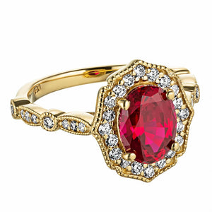 Antique style engagement ring reminiscent of Paris featuring a diamond accented halo and band with filigree detailing holding a 1ct oval cut lab created ruby in 14k yellow gold