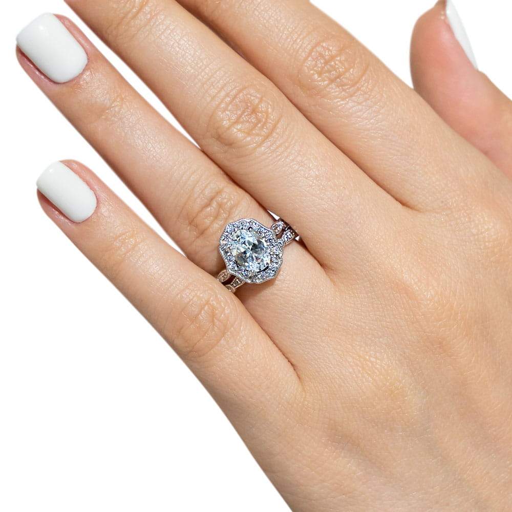 Shown with a 1.0ct Oval cut Lab-Grown Diamond with a diamond accented halo and filigree detailing in recycled 14K white gold with matching wedding band, can be purchased together at a discounted price