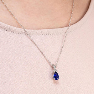 Diamond accented tear drop pendant with 1ct pear cut lab grown blue sapphire in 14k white gold shown worn