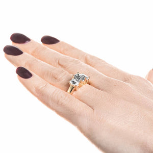 Three stone engagement ring with emerald cut lab grown diamonds in 14k yellow gold band worn on hand sideview