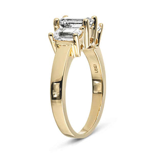 Three stone engagement ring with emerald cut lab grown diamonds in 14k yellow gold band shown from side