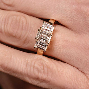 Unique ethical three stone engagement ring with emerald cut lab grown diamonds in 14k yellow gold band worn on hand